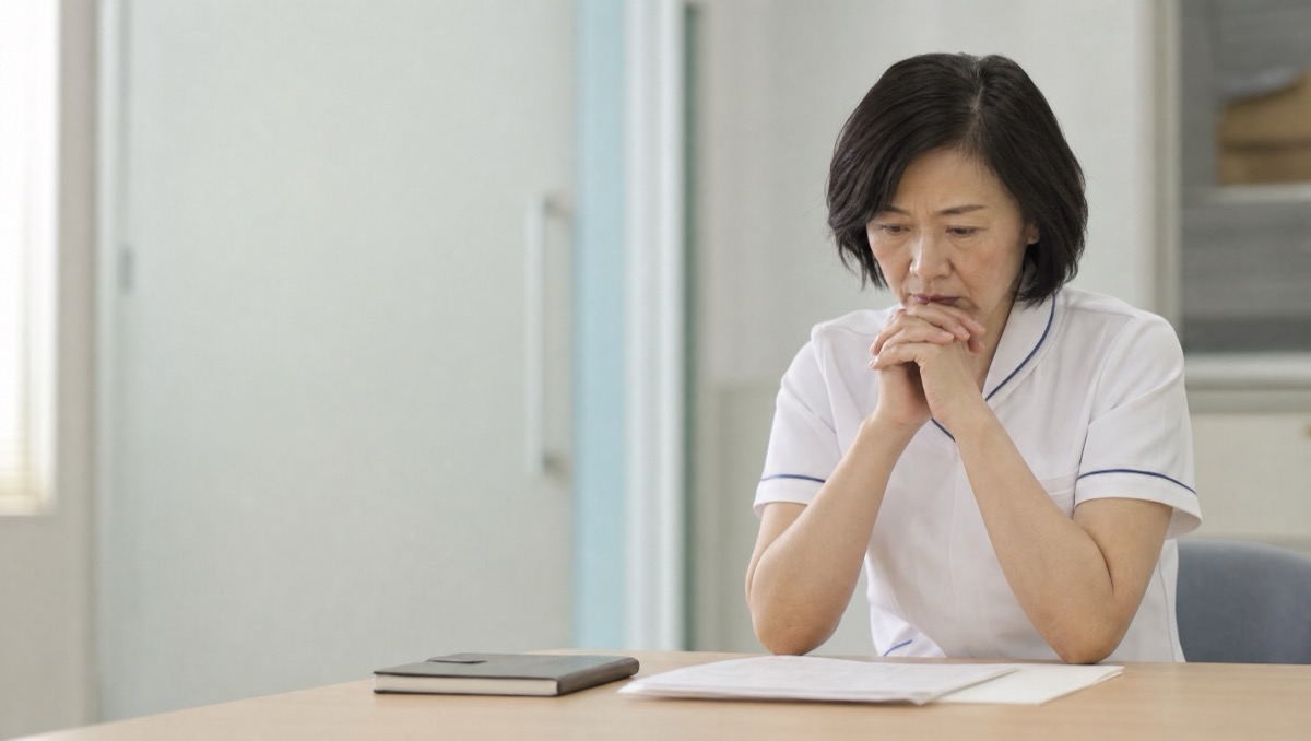 ナースステーション付近で静かに電話する看護部長らしき人物のイメージ
