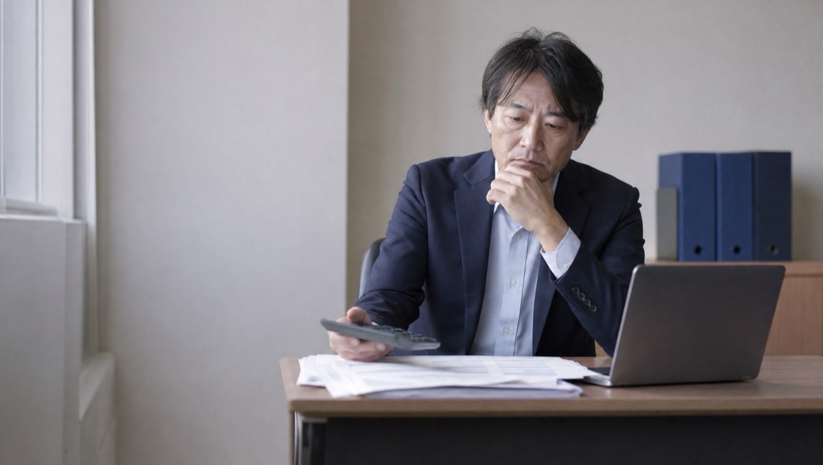 電卓と紹介会社の請求書、求人サイトの画面が並ぶ机のイメージ